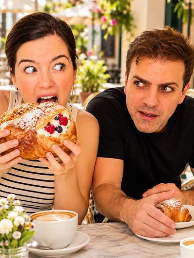 Couple at outdoor café — woman eating enormous pastry, man jealous with tiny croissant — comedy sketch