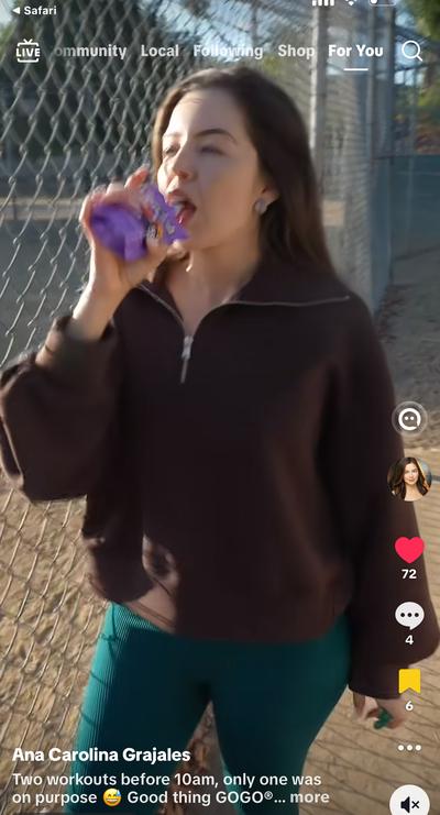 Ana eating GoGo squeeZ pouch outside by chain link fence